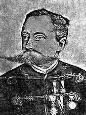 Photo en noir et blanc du torse et du visage d'un homme moustachu.