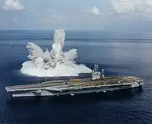 Photographie des gerbes d'eau projetées en l'air par l'explosion d'une bombe sous-marine, à proximité du navire.