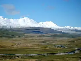 Vue en direction du sud depuis le plateau de l'Oukok en Russie avec la rivière Kalguty, affluent de l'Argout, au premier plan et une partie de la chaîne de l'Altaï avec la cime du Kujten Uul complètement à gauche à l'arrière-plan.
