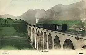 Carte postale en couleur du représentant le viaduc ferroviaire dans une vue à niveau, avec un train à vapeur le traversant, vers le tournant du XXe&nbsp;siècle..