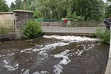 Vue d'une rivière en crue et d'un pont routier bientôt inondé.