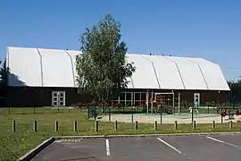 Vue d'un bâtiment en bois à haute toiture en toile.