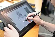 Dessinateur en cours de réalisation d'un personnage sur une tablette graphique.
