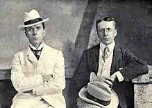 Deux hommes en costume, l'un blanc, l'autre sombre. Ressemblance de famille.