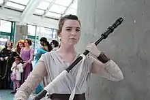 Femme brune tenant un bâton.