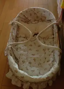 Berceau avec une cordelette de chaque côté pour le déplacer.