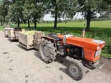 Tracteur avec remorques contenant la récolte de poires.