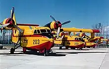 Trois avions canadairs jaunes et rouges stationnés dans un pélicandrome.