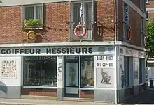 Photographie d'une bâtiment avec l'enseigne coiffeur.