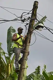 Photographie d'un homme accroché à un poteau.