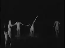 Scène de film montrant des gens nus courant vers l’océan.