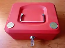 Petite cassette rouge avec une pièce de un euro et une autre de deux euros.