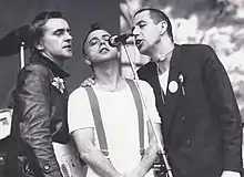 Photographie de trois hommes autour d'un micro.