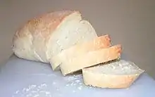 Photographie d’une miche de pain découpée en tranches.